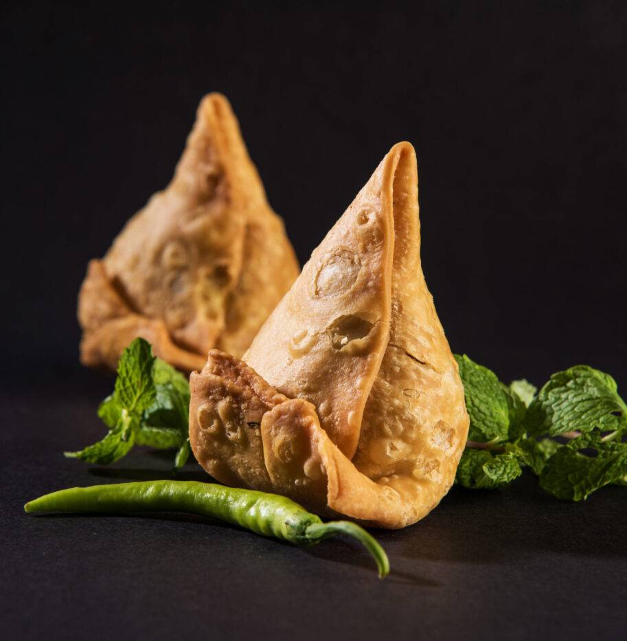 Veg Samosa is an Indian popular snack or junk food Served with fried green chilly, onion & chutney or ketchup